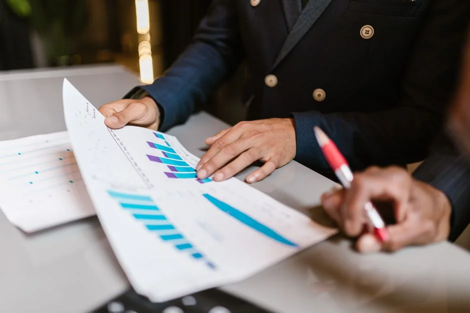 Un environnement de travail contemporain où des mains examinent des données marketing sur un ordinateur portable et des documents imprimés.